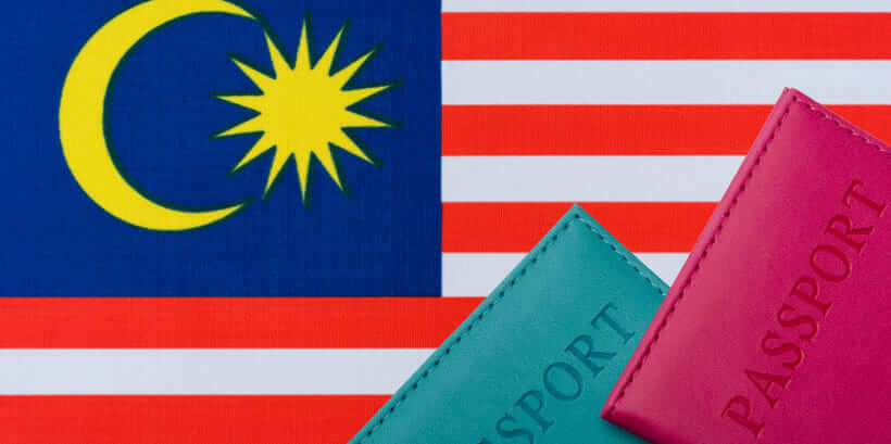 Two passports are placed in front of the Malaysian flag, symbolizing the ease with which travelers can apply for a Malaysia visa online from Dubai.